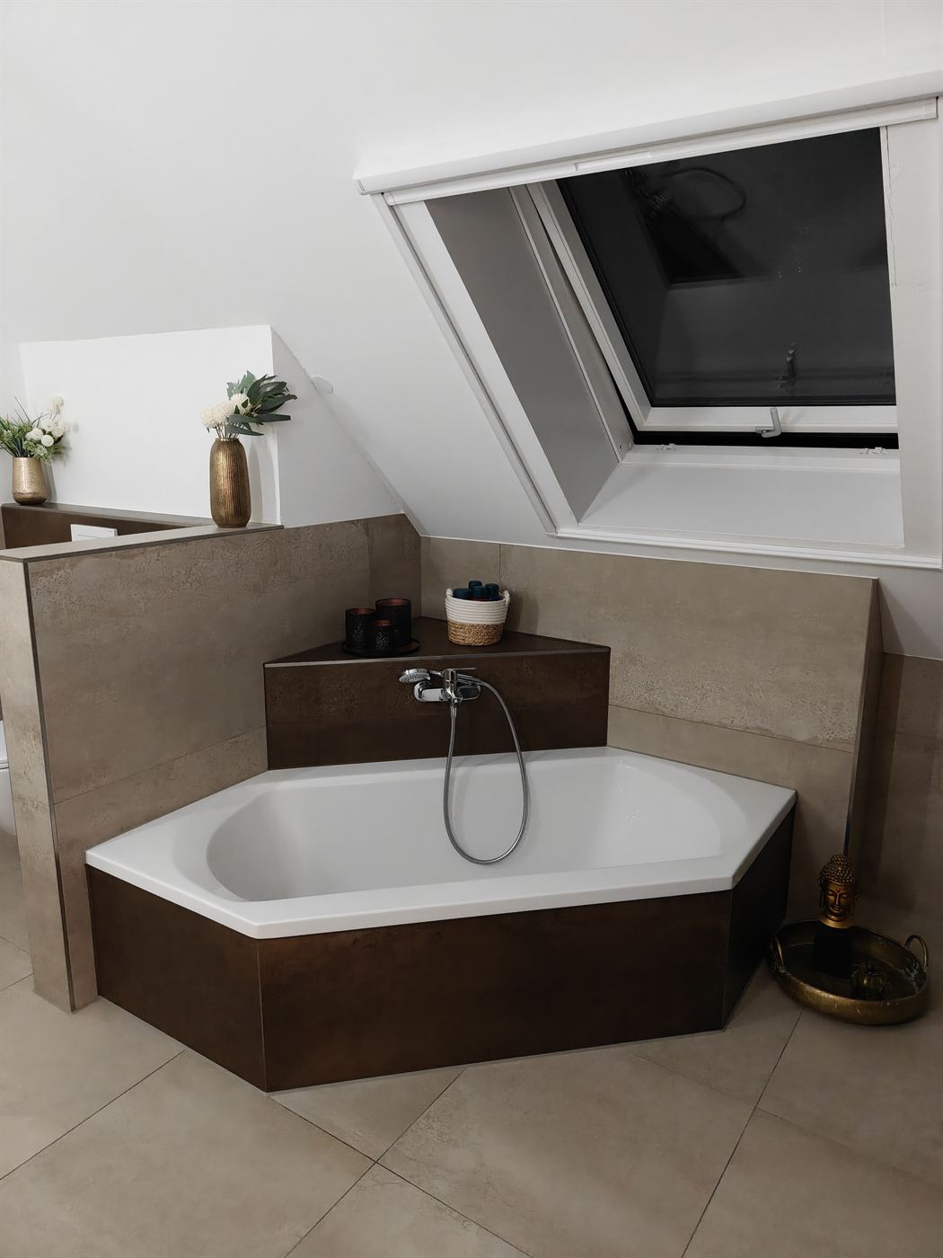 Sechseck-Badewanne in einer Nische unter der Dachschräge, Wannenschürze in Rostoptik gefliest, darüber ein Dachfenster